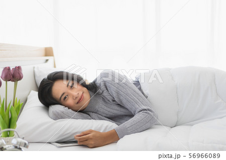 Woman lying on bed and using tablet in bedroom.. 56966089