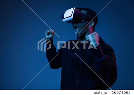 Young african-american man's using VR-glasses in neon light Young african-american man's using VR-glasses in neon light 56973065