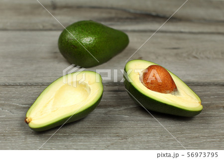 Two avocados, one cut in half, seed visible, on 56973795