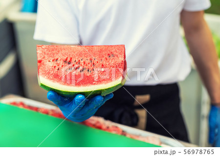 Cook in rubber gloves holding in hand and offering 56978765
