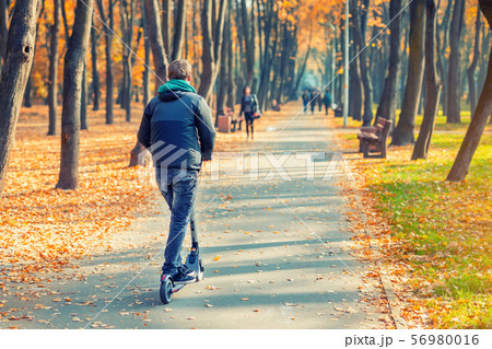 Young adult person riding modern electric scooter Young adult person riding modern electric scooter 56980016