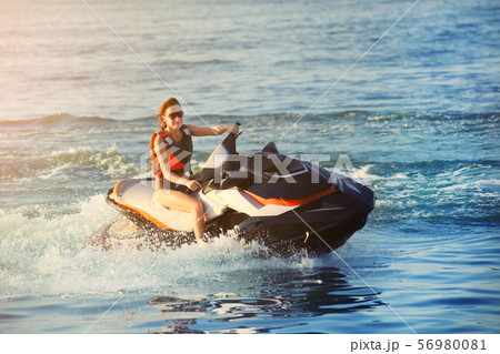 Young adult sporty caucasian woman riding jet ski 56980081