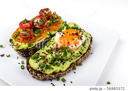 Sandwiches with avocado guacomole, egg and tomatoes, green leek and sesame seeds. Healthy breakfast 56983372