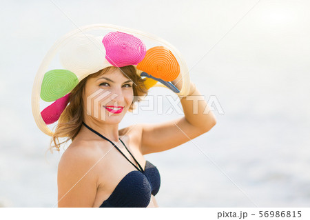 A brunette girl holds a hat on her head. A brunette girl holds a hat on her head. 56986815