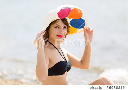 A brunette girl holds a hat on her head. A brunette girl holds a hat on her head. 56986816