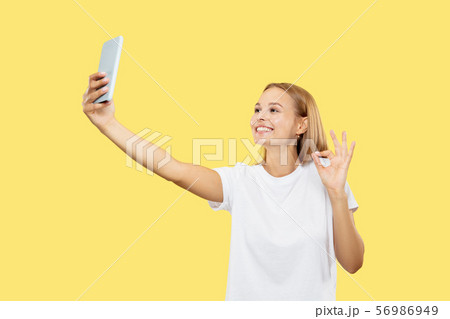 Caucasian young woman's half-length portrait on yellow background Caucasian young woman's half-length portrait on yellow background 56986949