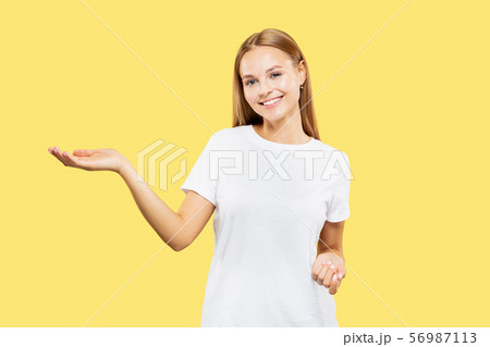Caucasian young woman's half-length portrait on yellow background 56987113