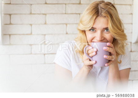 Happy pretty female is drinking hot beverage 56988038