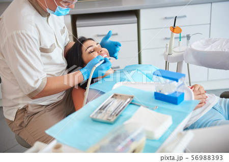 Dentist in protective mask is treating teeth 56988393