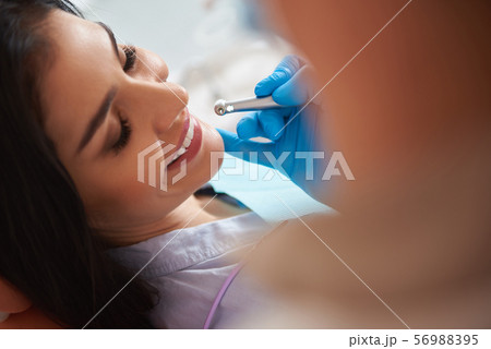 Happy young lady having dental procedure at dental clinic 56988395