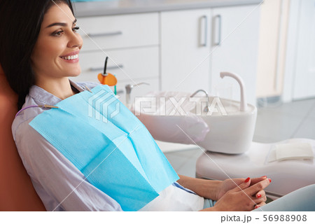 Happy young female sitting in dental chair 56988908