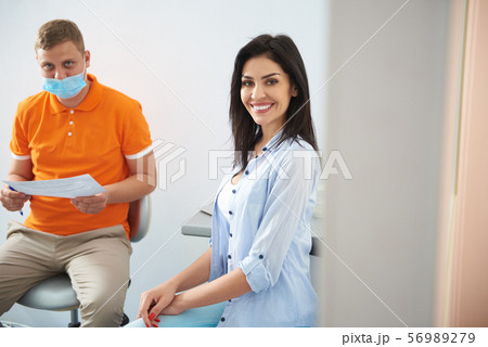 Young woman talking with dentist about results of orthopantomogram Young woman talking with dentist about results of orthopantomogram 56989279
