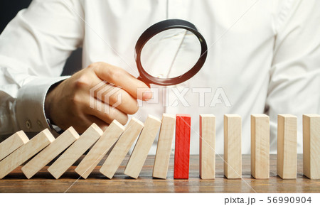 Businessman looks on collapse domino effect. Businessman looks on collapse domino effect. 56990904