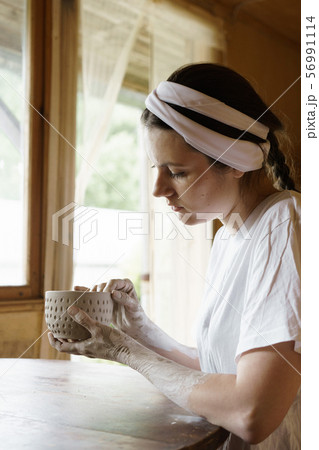 Beautiful young woman in a creative workshop sits at a table 56991114