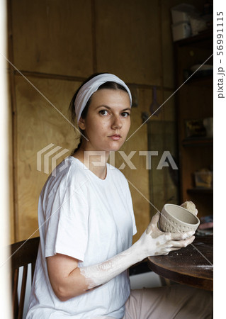 Beautiful young woman in a creative workshop sits at a table 56991115