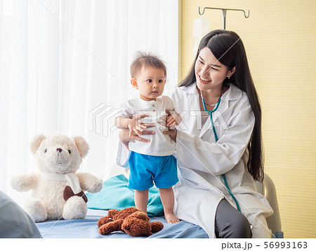 Beautiful doctor examination a baby boy on the patient bed. Beautiful doctor examination a baby boy on the patient bed. 56993163