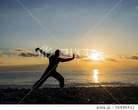 Martial Artist with orange sunset. Silhouette of a man practice whushu. Healthy lifestyle 56996432