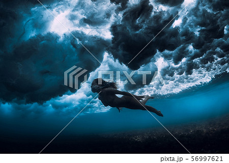 Woman in bikini dive without surfboard underwater with ocean wave. Duck dive under barrel wave 56997621