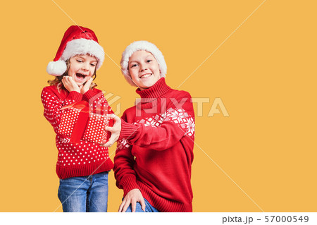 Boy handing Christmas present to surprised girl Boy handing Christmas present to surprised girl 57000549