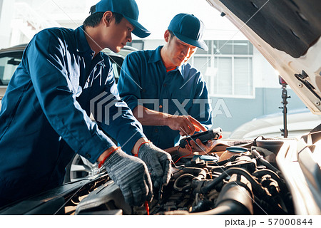 Car mechanics working with multimeter 57000844