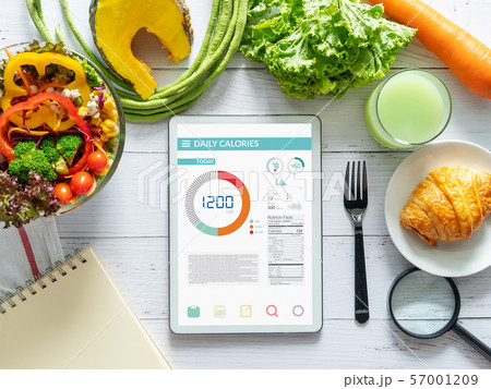 Calories counting , diet , food control and weight loss concept. tablet with Calorie counter application on screen at dining table with salad, fruit juice, bread and vegetable 57001209