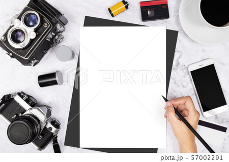 flat lay hand writing in a blank white page notebook decorated with vintage camera and photography tool on white marble background 57002291