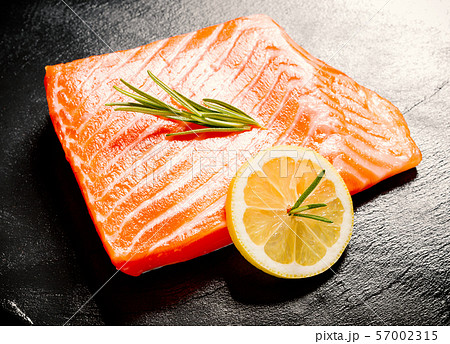 Juicy salmon fillet on black slate plate 57002315