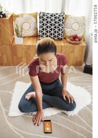 Young woman using yoga app 57002758