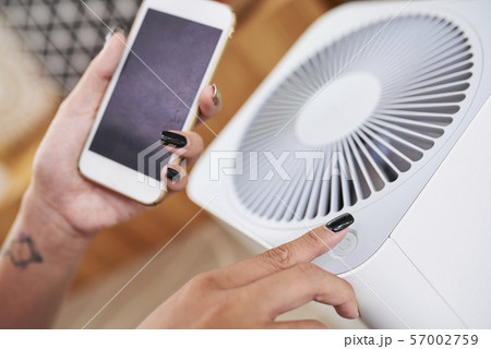 Woman turning on air conditioner 57002759