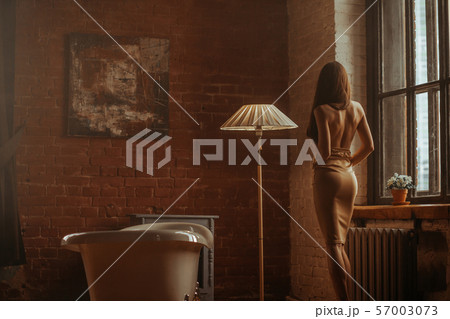 Elegant woman in decorated room with white tub Elegant woman in decorated room with white tub 57003073
