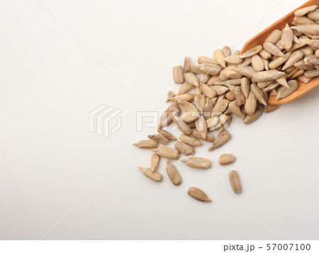 High angle view of natural shelled organic sunflower seeds on wooden spoon isolated on white background. It often eaten as a snack.  The seeds contain vitamin E. Food, snack concept. With copy space. 57007100