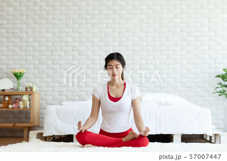 Attractive Asian woman practice yoga lotus pose to meditation in bedroom after wake up in the morning Feeling so comfortable and relax,Healthcare Concept Attractive Asian woman practice yoga lotus pose to meditation in bedroom after wake up in the morning Feeling so comfortable and relax,Healthcare Concept 57007447