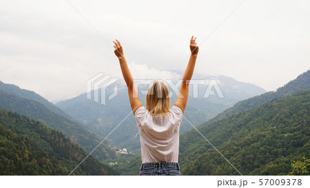 Cheering woman hiker open arms at mountain peak Cheering woman hiker open arms at mountain peak 57009378
