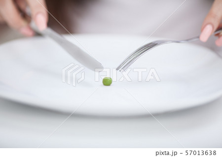 Diet. Suffering from anorexia. Cropped image of girl trying to put a pea on the fork Diet. Suffering from anorexia. Cropped image of girl trying to put a pea on the fork 57013638