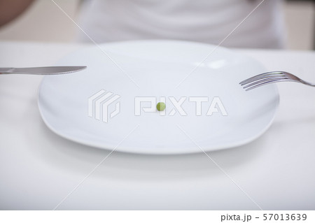 Diet. Suffering from anorexia. Cropped image of girl trying to put a pea on the fork Diet. Suffering from anorexia. Cropped image of girl trying to put a pea on the fork 57013639