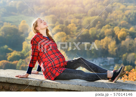 Pregnant woman lies on a hill with her eyes 57014146