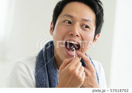 糸ようじでオーラルケアする若い日本人男性 57018702