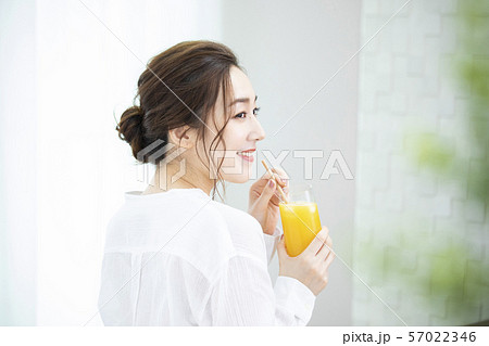 オレンジジュースを飲む女性 エコストローの写真素材