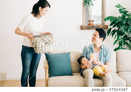 赤ちゃんにミルクを飲ませる父親と家事をする母親 57024397