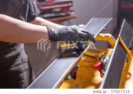Work and repair concept - a man's hands repairing the ski by rubbing a paraffin Work and repair concept - a man's hands repairing the ski by rubbing a paraffin 57027113