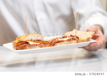 Chef preparing delicious typical Spanish food, bacon tapa or Pintxo of bacon. Chef preparing delicious typical Spanish food, bacon tapa or Pintxo of bacon. 57028547