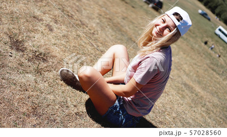 The girl in a cap and shorts in the mountains sits on the grass 57028560