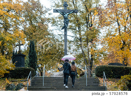 Man and woman walking up steps on cemetery towards a cross 57028576