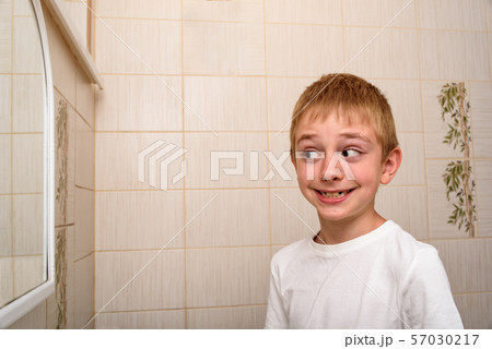 Smiling scholboy looks in the bathroom mirror. Smiling scholboy looks in the bathroom mirror. 57030217