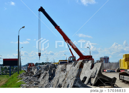 Auto crane loads an old concrete slab into a dump truck at a construction site. Auto crane loads an old concrete slab into a dump truck at a construction site. 57036833