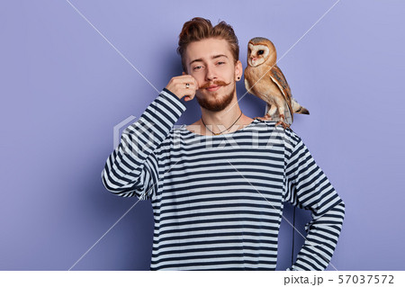 cunning guy taking money from tourist for taking a pictire with an owl 57037572