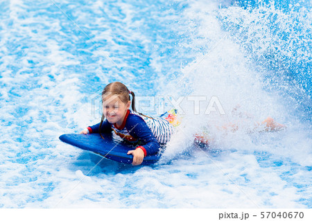 Little girl surfing in beach wave simulator 57040670