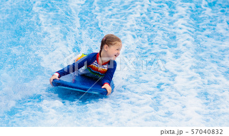 Little girl surfing in beach wave simulator 57040832
