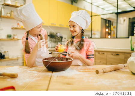 Little girls cooks in caps sniffing vanilla powder Little girls cooks in caps sniffing vanilla powder 57041531