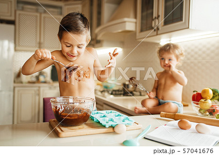 Little kids tastes melted chocolate on the kitchen 57041676